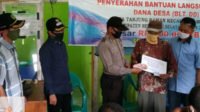 Kanit Binmas Aipda Amrizal berkesempatan membantu penyerahan BLT DD Tanjung Raman, Kamis (21/5) pagi.