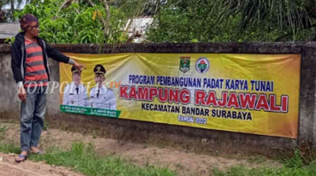 Plang informasi proyek ala Pemerintah Kampung Rajawali terpampang di pagar tembok milik warga